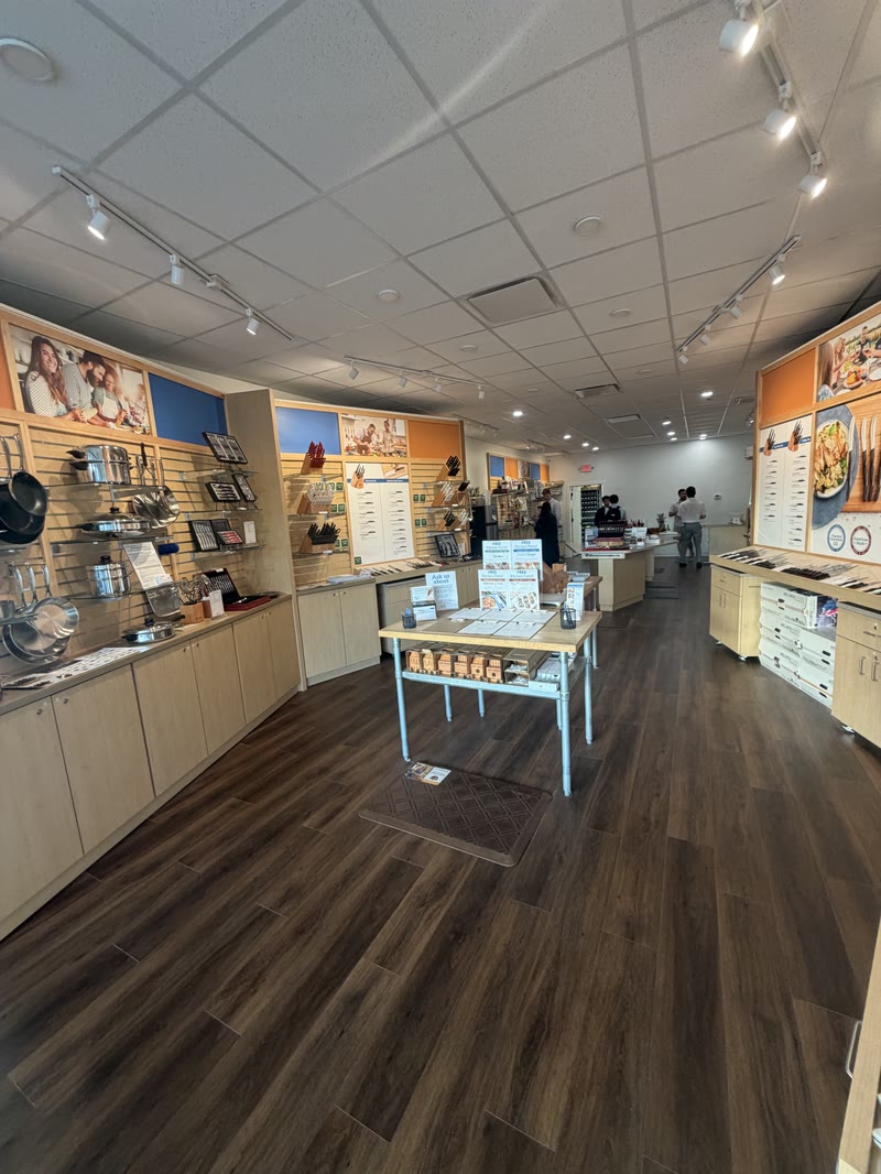 Inside the Cutco store in Wilmette: knife and shear displays along both walls, a demo table in the middle, and cookware on the left.